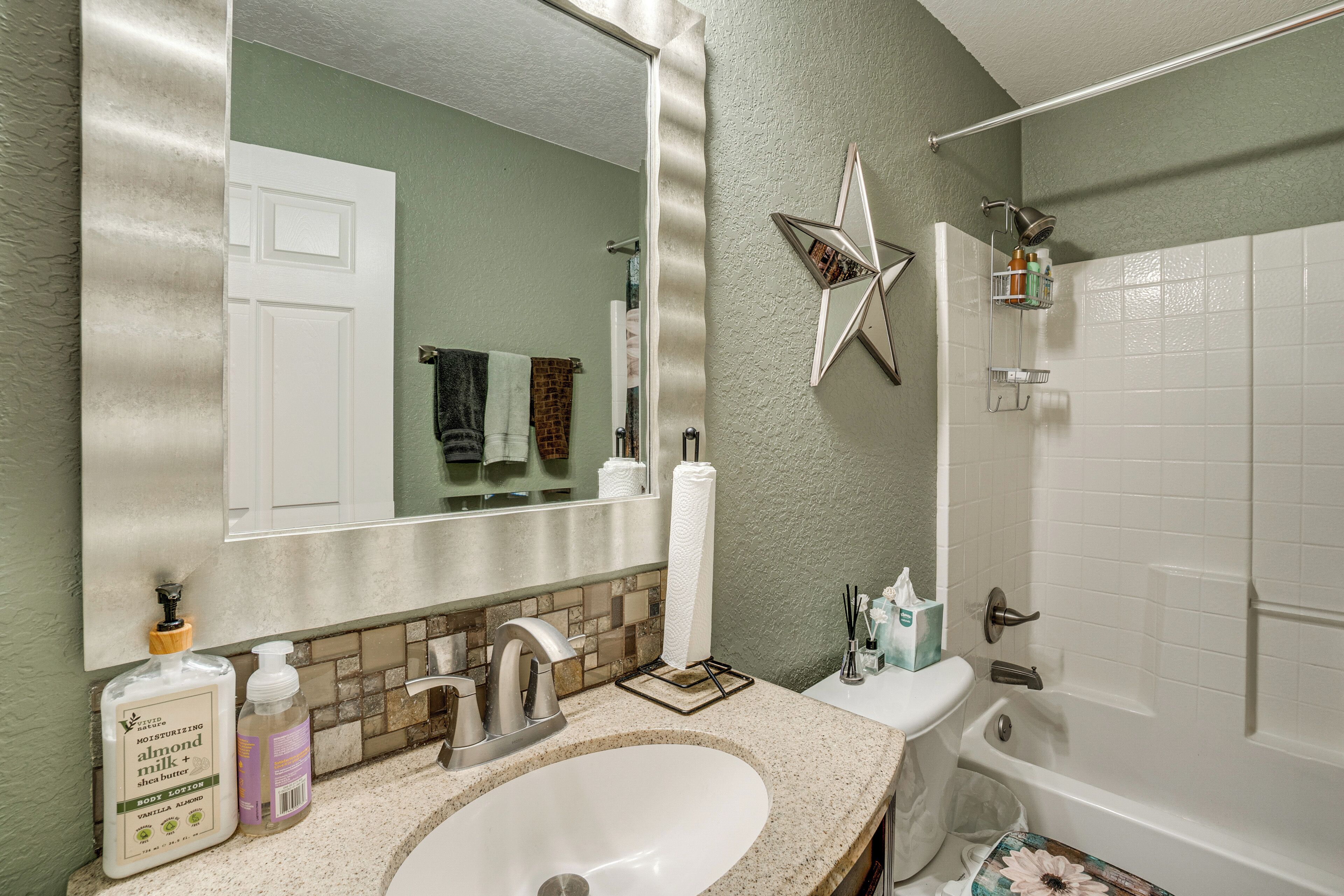 A bathroom with a sink, mirror, towel rack, and a shower area.