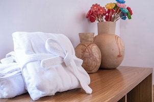 Una mesa de madera con toallas blancas dobladas y dos jarrones de cerámica con flores.