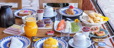 Una mesa de desayuno con platos de comida, una cafetera y una jarra de jugo de naranja.