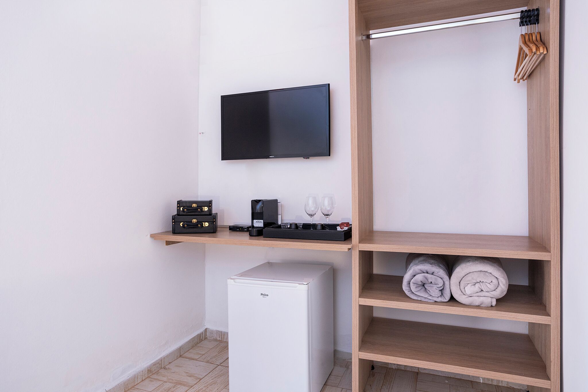 A compact kitchenette with a small fridge, a coffee maker, and a speaker.
