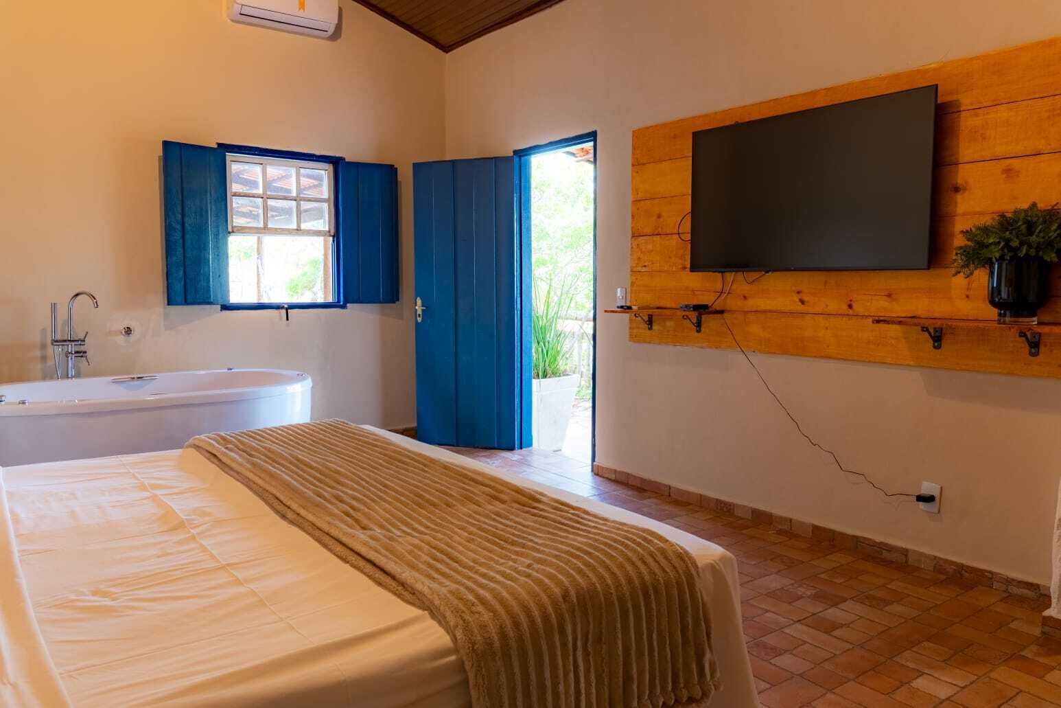 Ein Schlafzimmer mit einem großen Bett, einer Badewanne und einem an einer Holzwand montierten Fernseher.