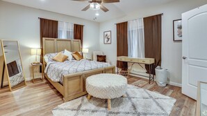 A bedroom with a bed, bedside tables, a desk, a chair, a ceiling fan, and a door. - Sleek & Central! Houston Stay Near Med Center (Houston)