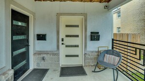 A covered porch with a door, a chair, and a metal railing. - Sleek & Central! Houston Stay Near Med Center (Houston)