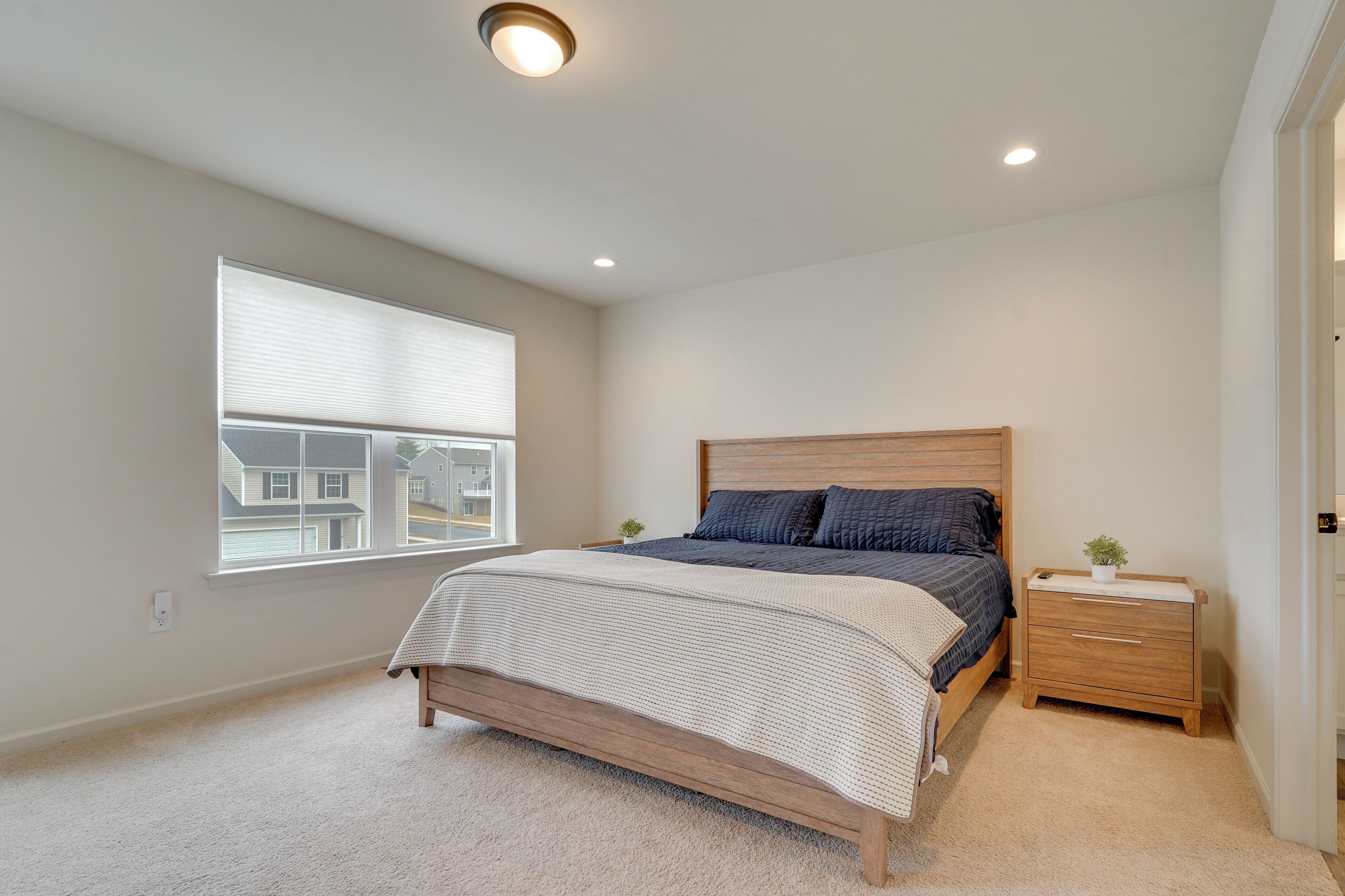 A bedroom with a bed, bedside table, and a window with blinds.