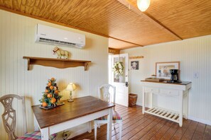 Ein Holztisch mit einem Weihnachtsbaum, ein weißer Stuhl, eine weiße Kommode mit einer Kaffeemaschine und eine Klimaanlage an der Wand.