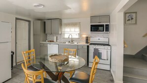 A compact kitchen with a glass dining table, wooden chairs, a microwave, and a stove. - Work, Relax & Explore The 'Burgh! McKeesport Home (McKeesport)