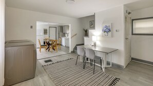 A modern kitchen with white cabinets, a dining area with wooden chairs, and a small table with a lamp. - Work, Relax & Explore The 'Burgh! McKeesport Home (McKeesport)