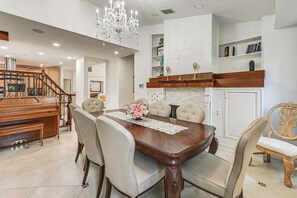 A dining area with a wooden table, six chairs, a chandelier, and a fireplace. - Poolside Oasis: Group-Friendly Getaway in Naples! (Naples)