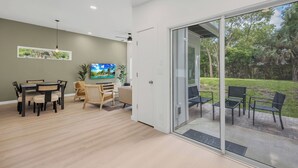 Ein modernes Interieur mit Essbereich, Fernseher und einer Schiebetür zu einer Terrasse.
