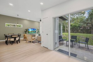 Ein modernes Interieur mit Essbereich, Fernseher und einer Schiebetür zu einer Terrasse.