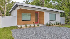 Ein modernes Haus mit roter Tür, großen Fenstern und einer Auffahrt mit Kies.