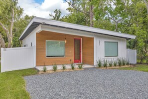 Ein modernes Haus mit roter Tür, großen Fenstern und einer Auffahrt mit Kies.