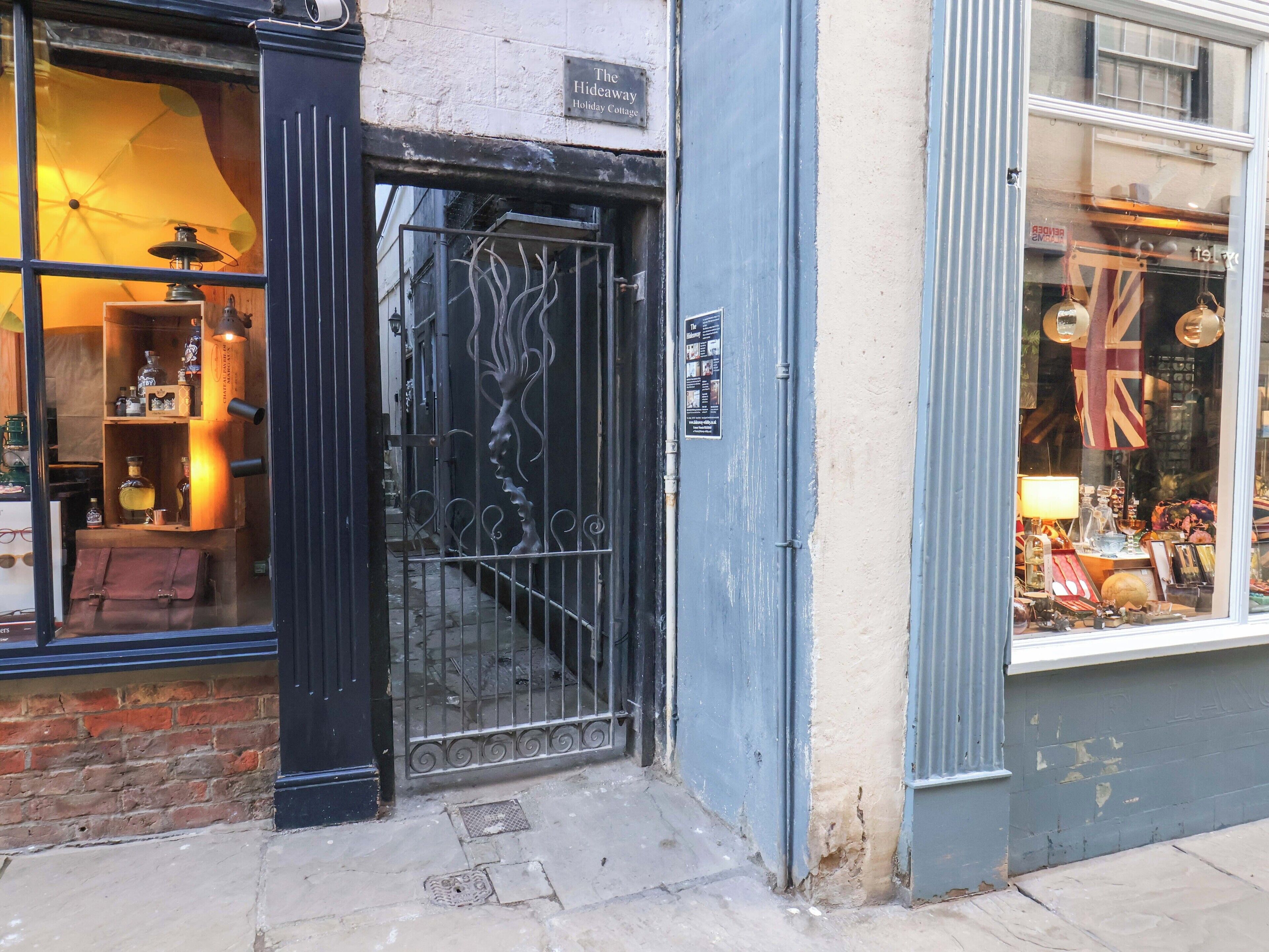 Entrada de um hotel boutique com um portão de metal, parede de tijolos e vitrine.