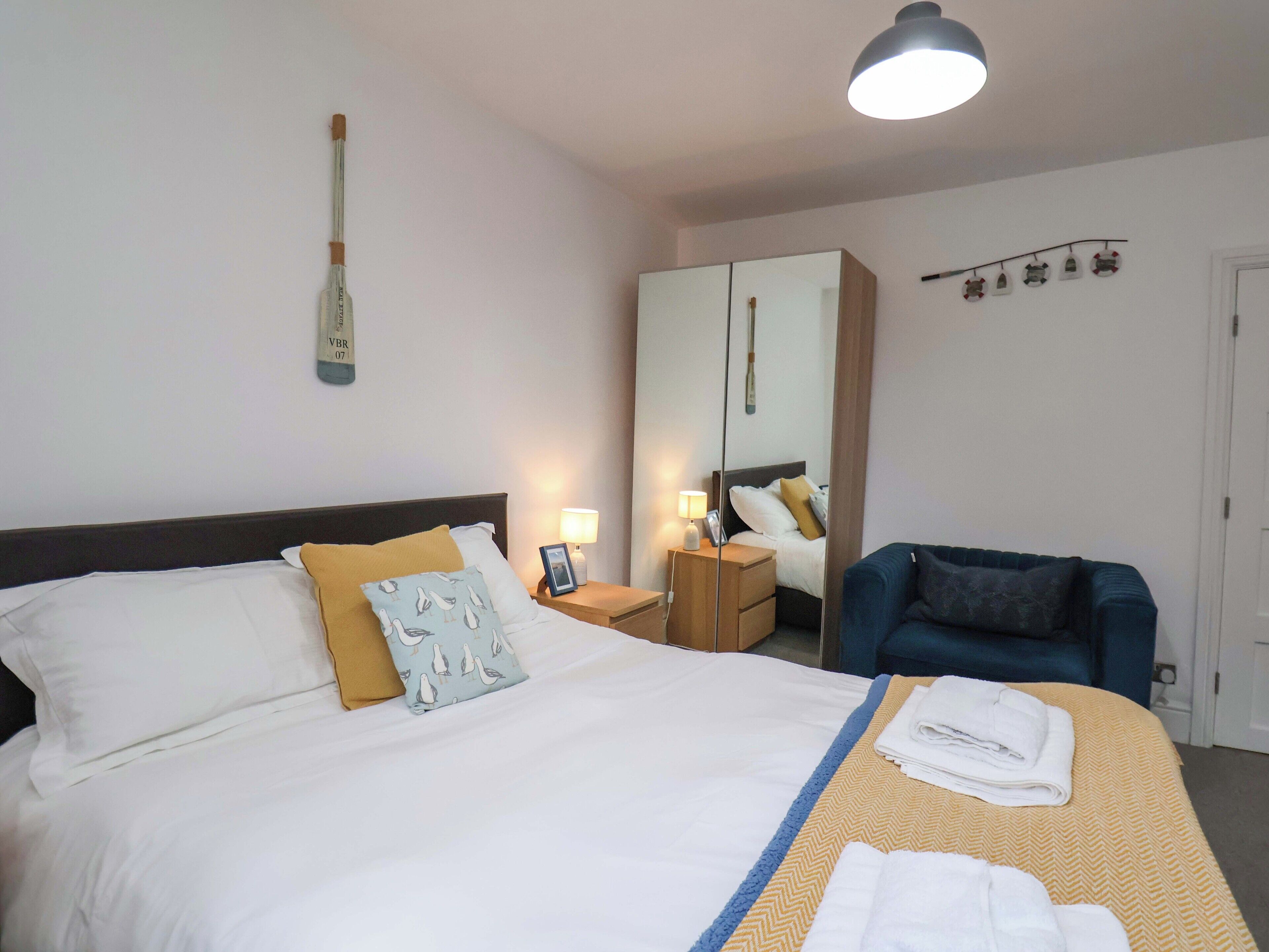 Een hotelkamer met een bed, nachtkastjes, een stoel, een kledingkast en een spiegel.