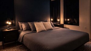 Een slaapkamer met een groot bed, twee nachtkastjes met lampen, een grote spiegel en een raam.