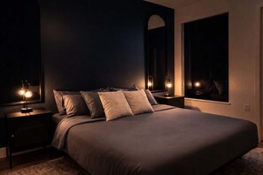 Ein Schlafzimmer mit einem großen Bett, zwei Nachttischen inklusive Lampen, einem großen Spiegel und einem Fenster.