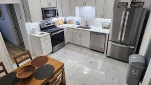 A modern kitchen with white cabinets, a stainless steel refrigerator, and a dining area with wooden chairs and a table. - 3-bedroom two story house in tranquil Metropolis with cool AC breeze (Metropolis)