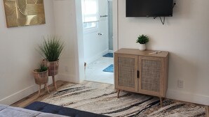 A bedroom with a bed, a television, a cabinet, and a door leading to another room. - 3-bedroom two story house in tranquil Metropolis with cool AC breeze (Metropolis)
