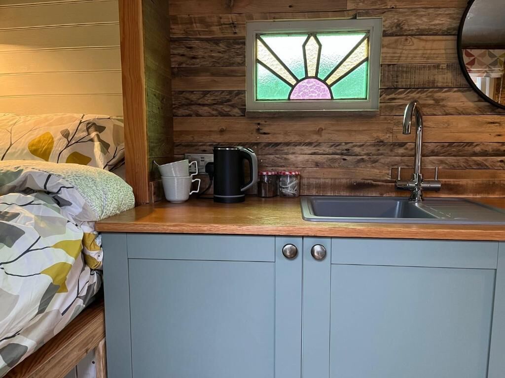 A compact kitchen with a wooden countertop, a sink, and a window with a stained glass design.