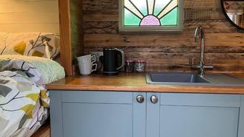 A compact kitchen with a wooden countertop, a sink, and a window with a stained glass design.