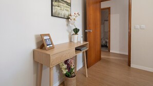 A wooden desk with a framed certificate, a potted orchid, and a small plant. A wooden door is open to a hallway. - Apartment 'Sérénité' with Balcony, Wi-Fi and Air Conditioning (Ponta Delgada)