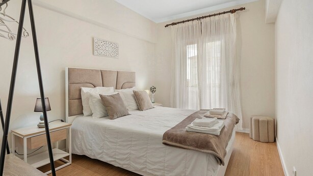 A bedroom with a bed, bedside table, lamp, and curtains. - Apartment 'Sérénité' with Balcony, Wi-Fi and Air Conditioning (Ponta Delgada)