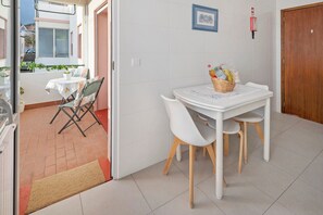 A small dining area with a table and chairs, a wicker basket with fruits, and a view of the outside. - Apartment 'Sérénité' with Balcony, Wi-Fi and Air Conditioning (Ponta Delgada)