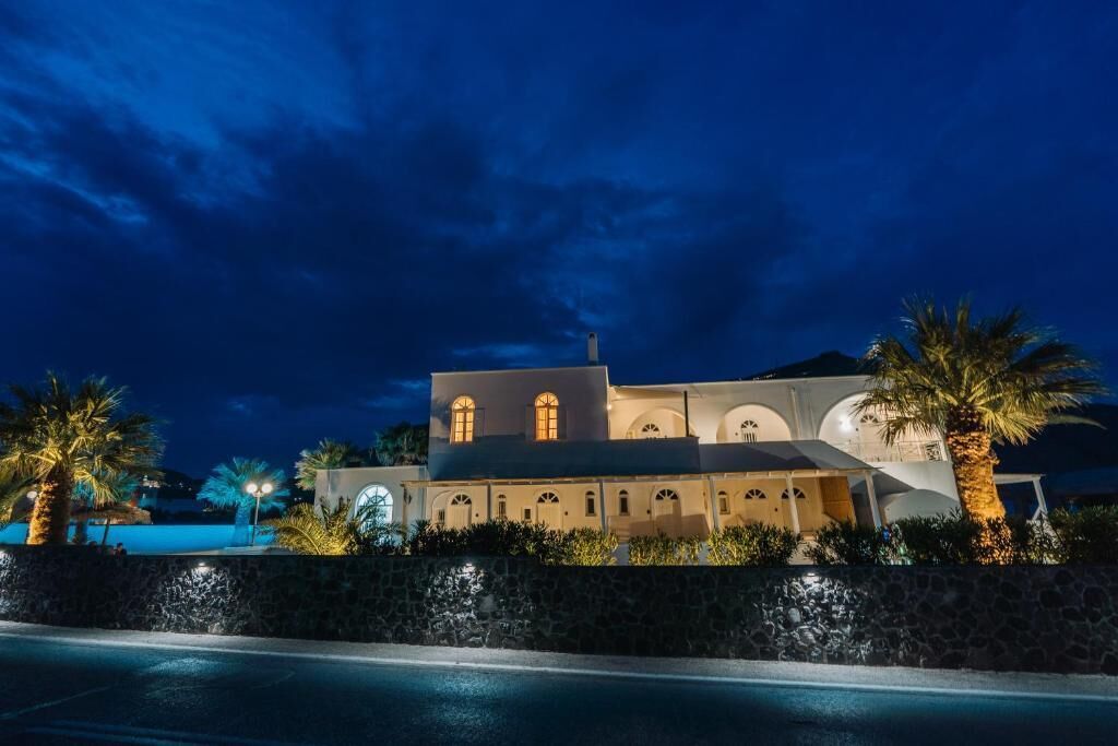 A large building with multiple arches and a stone wall in front.
