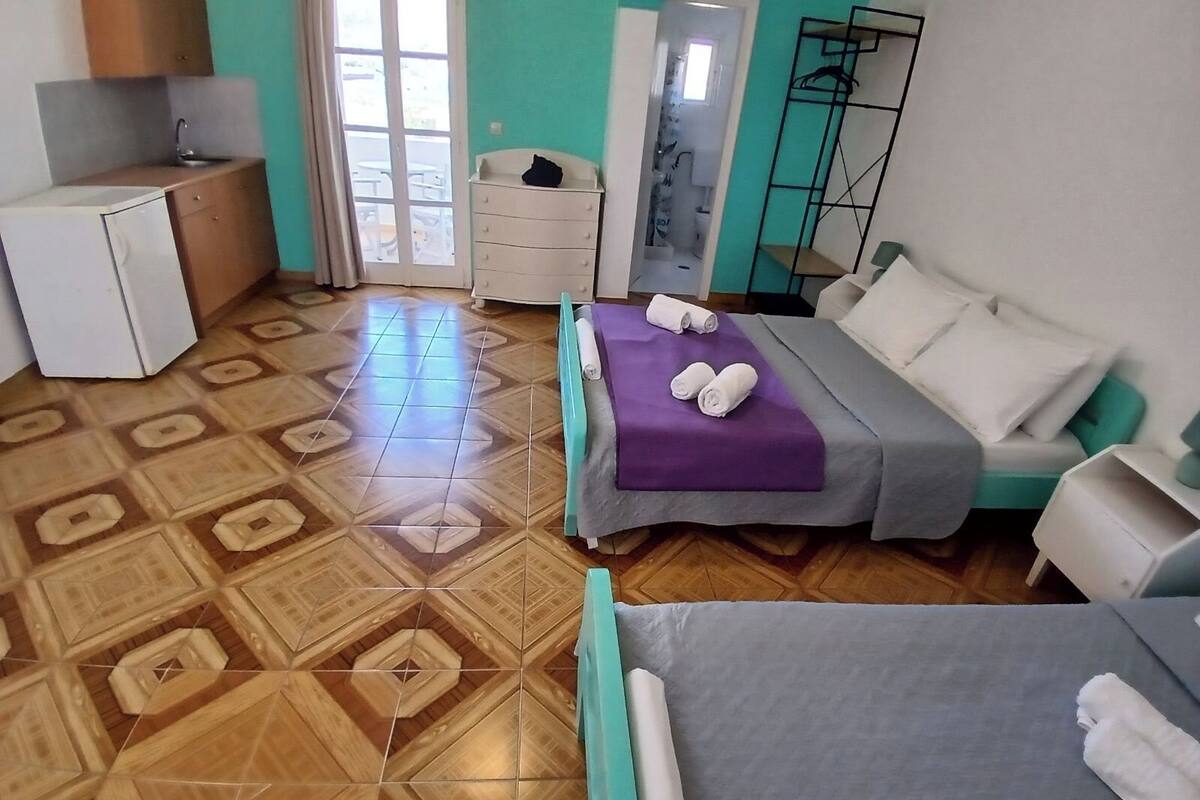 A room with a bed, a desk, a chair, a wardrobe, and a bathroom.
