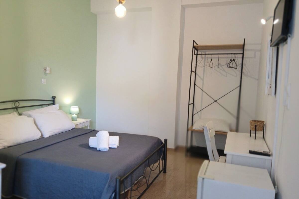 A bedroom with a bed, bedside table, lamp, and a small table with a chair.