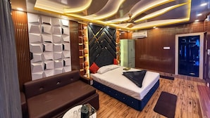 Een moderne hotelkamer met een bed, een bank, een eettafeltje en een plafond met bijzondere verlichting.