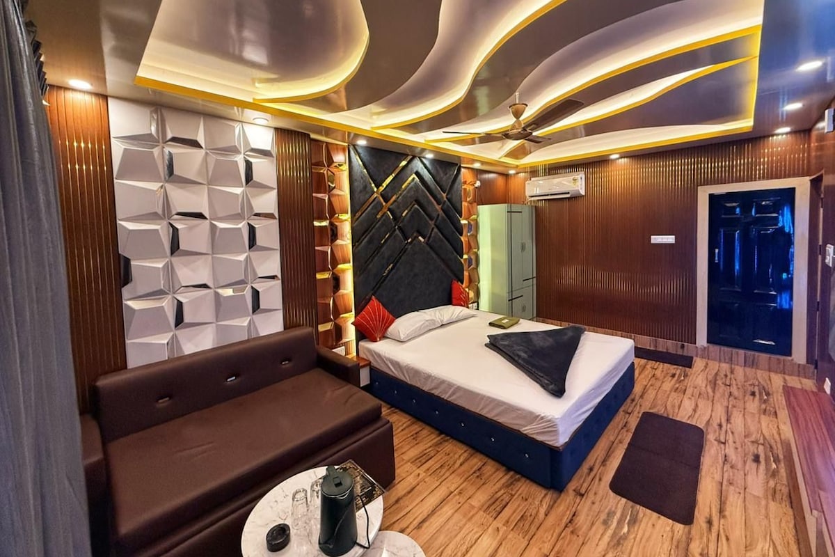 A modern hotel room with a bed, a sofa, a small table, and a ceiling with unique lighting.