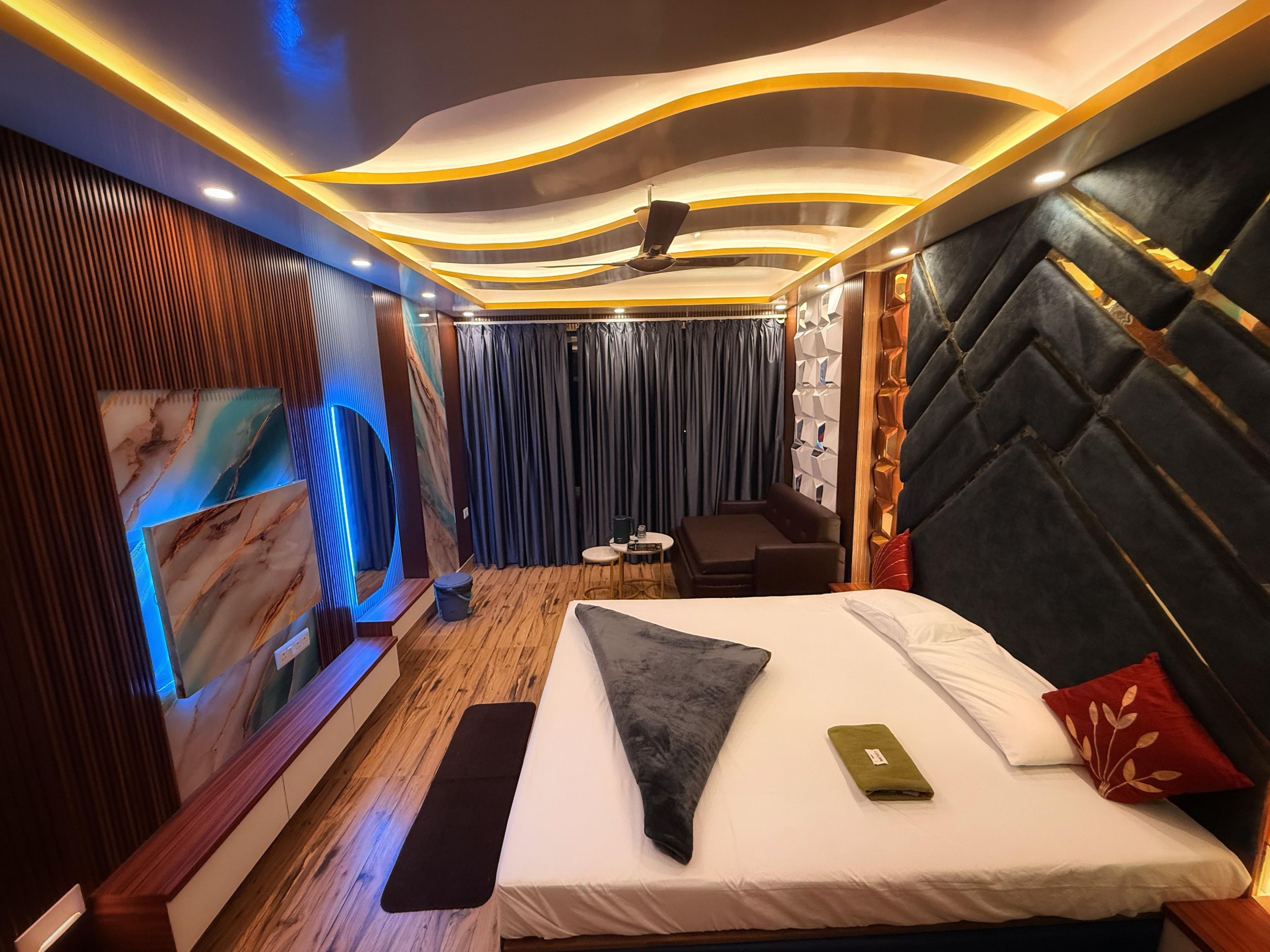 A modern hotel room with a bed, a seating area, and a wall-mounted artwork.