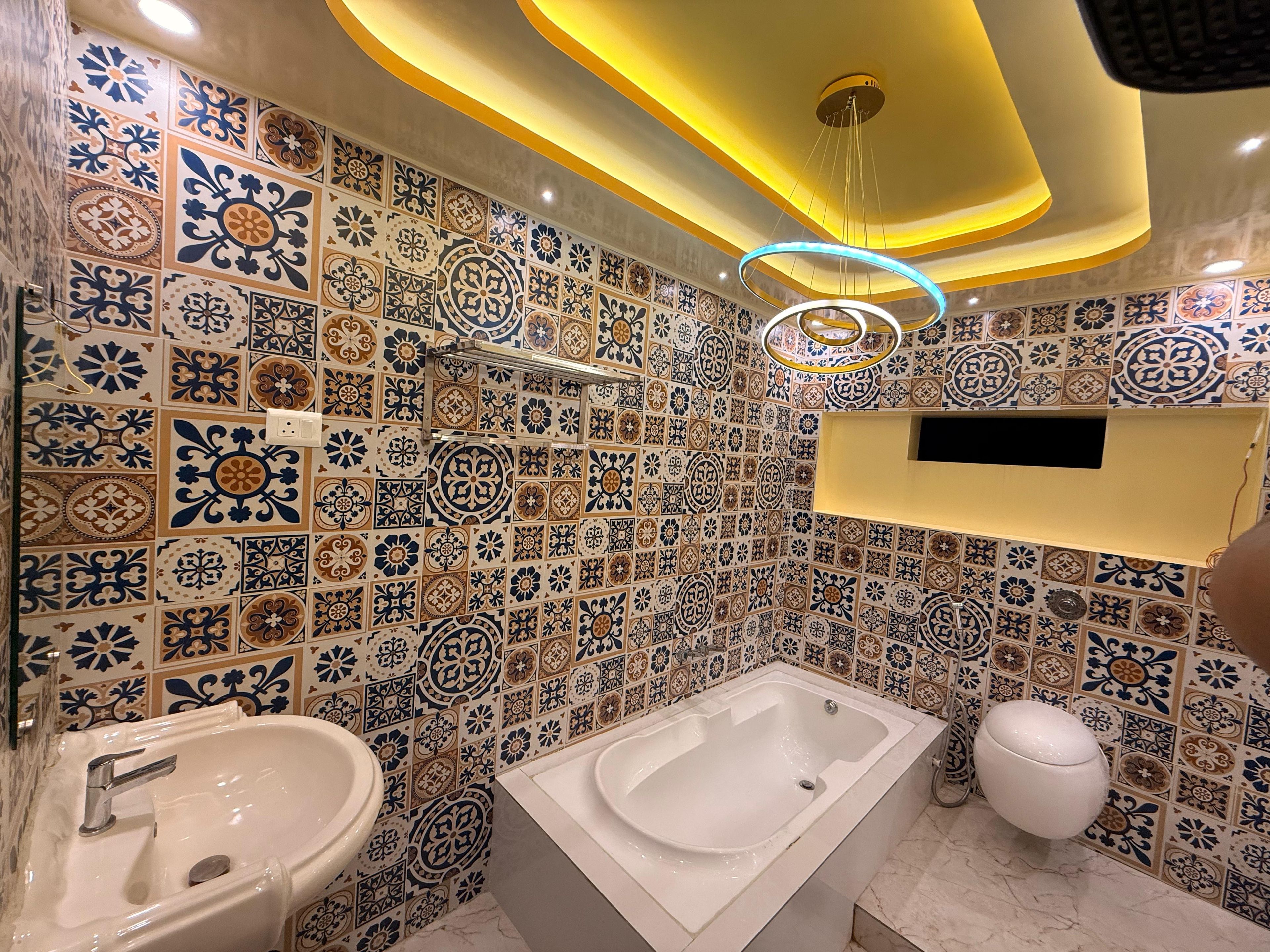 Un baño con bañera, lavamanos e inodoro, que presenta diseños decorativos en azulejos e iluminación empotrada.