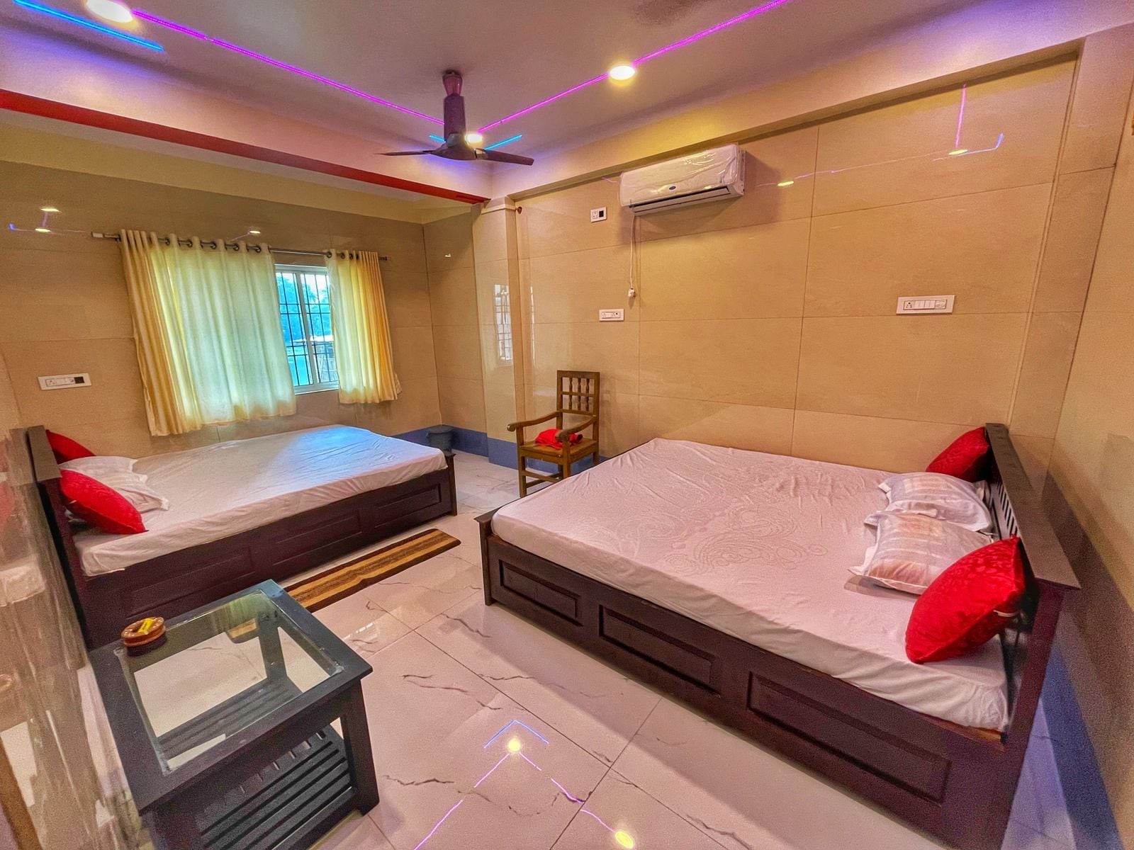 Une chambre d’hôtel avec deux lits, un ventilateur de plafond, un appareil de climatisation et une fenêtre avec des rideaux.