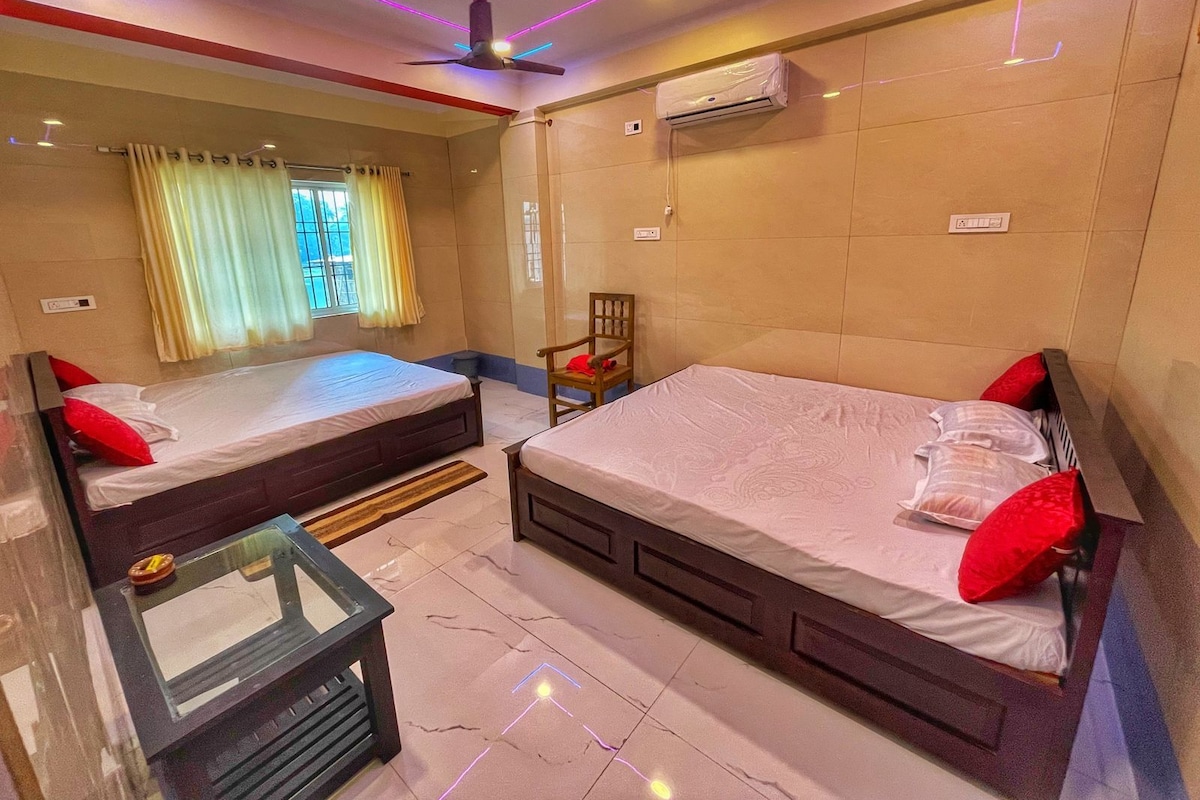 A hotel room with two beds, a ceiling fan, an air conditioning unit, and a window with curtains.
