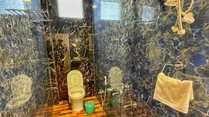 Een badkamer met een houten vloer, een toilet, een bidet en een handdoek aan de muur.