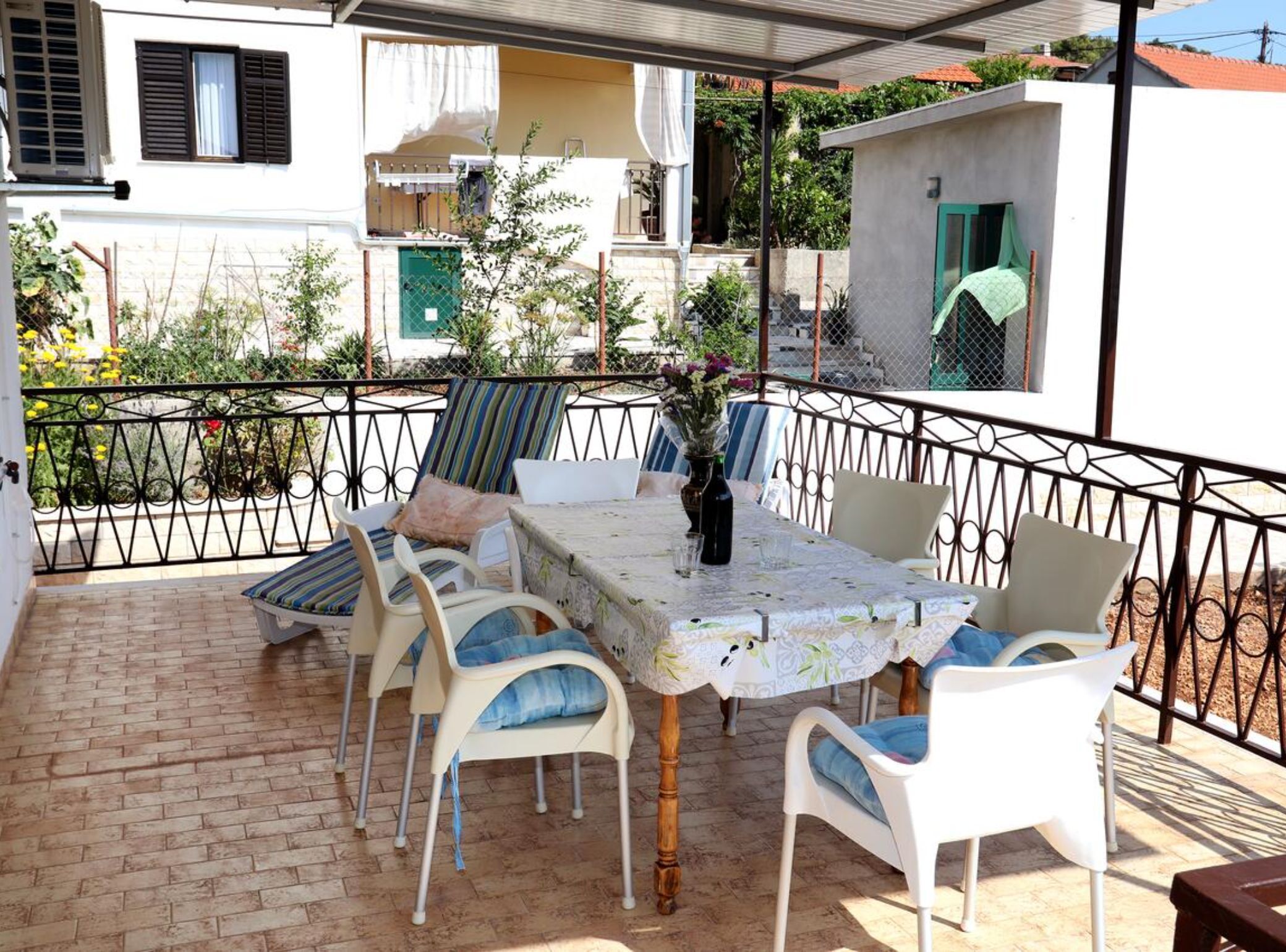 A patio with a table and chairs, surrounded by a metal fence, with buildings in the background.