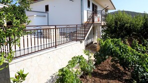 Un bâtiment blanc avec un mur en pierre, une clôture en métal et une antenne parabolique.