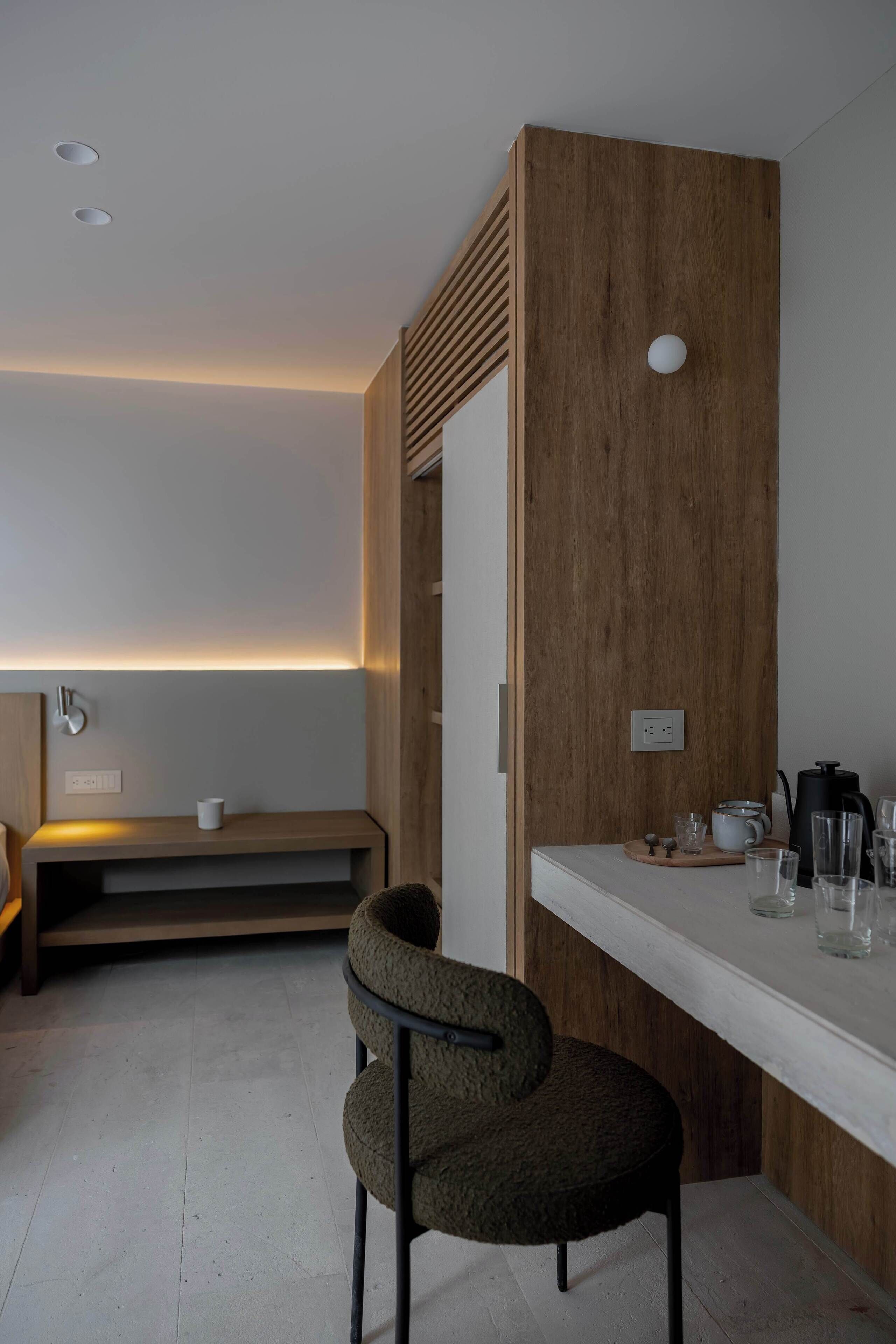 Una habitación moderna y minimalista con un panel de madera decorativo, una encimera blanca y una silla.