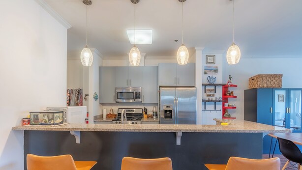A modern kitchen with a central island, bar stools, and pendant lighting. - Master King plus 2 Queens by NYC & onsite gym (Jersey City)
