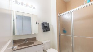 A bathroom with a sink, toilet, and glass shower enclosure. - Master King plus 2 Queens by NYC & onsite gym (Jersey City)