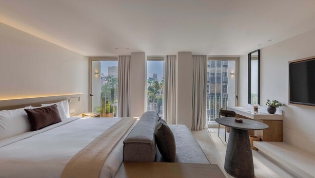 A modern hotel room with a large bed, a bench, a small table, and a TV. - A Stone Studio Beside Chapultepec (Ciudad de México)