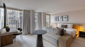 A modern hotel room with a large bed, a sofa, a small table, and a desk with a plant. - A Stone Studio Beside Chapultepec (Ciudad de México)