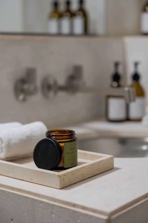 Ein Badezimmer mit Marmorplatte, einer Flasche grüner Flüssigseife und einem weißen Handtuch.