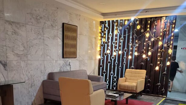 Een moderne woonkamer met marmeren vloeren, twee banken, een salontafel en een decoratieve wand met lichtslingers.