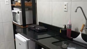 Een kleine keuken met een koelkast, magnetron en een spoelbak.