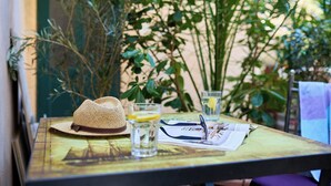 Une table avec un chapeau de paille, des lunettes, un journal et un verre d’eau.