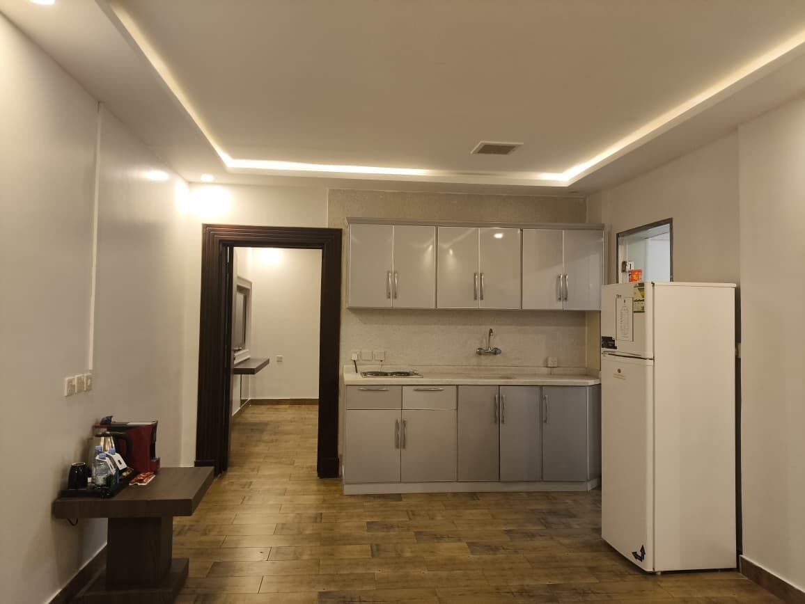 A compact kitchen with white cabinets, a built-in dishwasher, and a refrigerator.