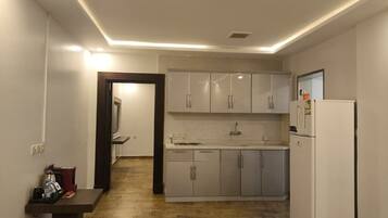 A compact kitchen with white cabinets, a built-in dishwasher, and a refrigerator.